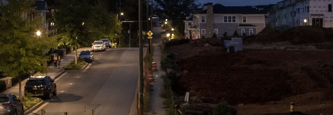 a street at night with cars parked on the side of the road