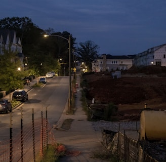 a street at night with cars parked on the side of the road